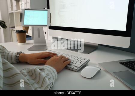 Softwareentwicklung und Codierungs-Workflow, Programmierer arbeitet an Computer und Tablet mit Quellcode in moderner Büroumgebung für Tech-Projekt Stockfoto
