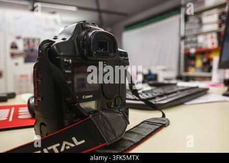 Rom, Italien 16. September 2026: Canon-DSLR-Kamera mit Schultergurt, die auf einem Schreibtisch liegt, bereit für Photowork in einem professionellen Studio- oder Büroumfeld Stockfoto