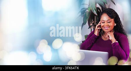 Schöne selbstbewusste afrikanische Geschäftsfrau, die ein Telefonat führt, während sie an einem Laptop arbeitet, umgeben von weichen Bokeh-Lichtern in einem modernen Arbeitsbereich Stockfoto
