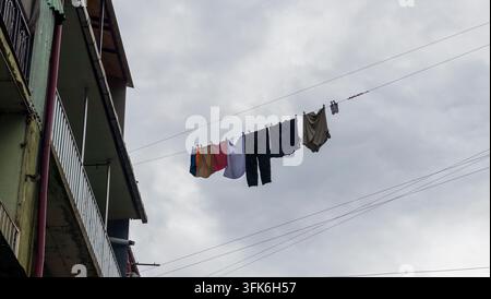 Niedrigwinkelaufnahme von Wäsche und Kleidung, die zum Trocknen auf einer Leine vor einem Wohnhaus aufgehängt ist. Stockfoto