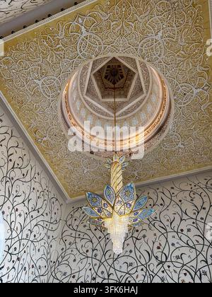Abu Dhabi, Vereinigte Arabische Emirate – 15. Oktober 2023: Blick auf florale Mosaikwände und einen kunstvollen Kronleuchter, der von der gewölbten Decke im Inneren des Shei hängt Stockfoto