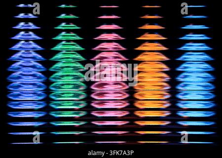 Abstrakte Vollbild-Fotografie von lebendigen Regenbogen-Neonlicht-Equalizer-Spektrumsäulen, die durch geriffeltes Glas auf schwarzem Hintergrund scheinen. Konzept von Klang Stockfoto