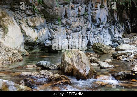Sanzhanxi-Fluss in Taroko, Hualien. Klares Wasser fließt über Felsen. Steile Felsabbrüche säumen das Wasser. Üppige Vegetation wächst entlang der Wände. Stockfoto