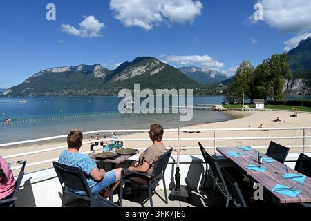 Touristen oder Gäste in einem Außenrestaurant mit Seeblick über den Lac d’Annecy von Saint Jorioz aus, französische Alpen, Haute-Savoie, Frankreich Stockfoto