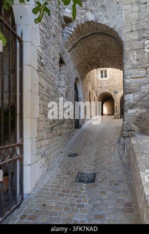 Scenische vertikale Stadtansicht einer alten Kopfsteinpflasterstraße mit gewölbtem Tunnel im malerischen mittelalterlichen Dorf Vézénobres, Gard, Frankreich Stockfoto
