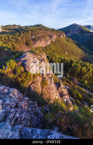 Eine malerische Luftaufnahme zeigt schroffe felsige Klippen und weite, sanfte grüne Hügel unter einem hellen Himmel während einer Wanderung in Portugal. Stockfoto