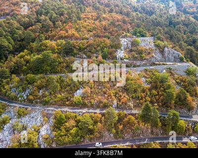 Lovcen-Serpentine Montenegro windet sich über felsige Waldhänge. Die Bergstraße windet sich durch herbstlich gefärbte Hügel, mit Autos auf asphaltierten Kurven und Stein Stockfoto
