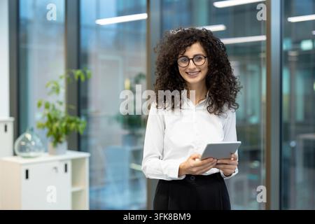 Geschäftsfrau mit Tablet im modernen Büro, professionelle Frau nutzt digitales Gerät für Unternehmenskommunikation und Projektmanagementaufgaben am Arbeitstisch. Stockfoto