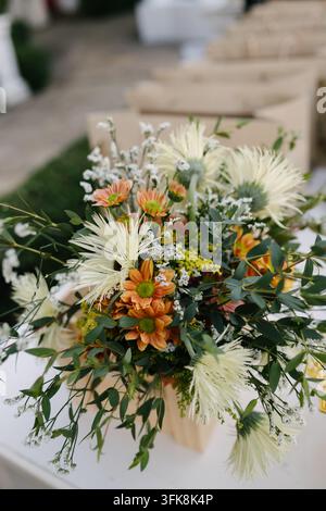 Schöner frischer Blumenstrauß mit weißen Chrysanthemen und orangefarbenen Gänseblümchen auf einem weißen Tisch Stockfoto