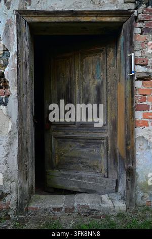 Alte verwitterte Holztür in einem verlassenen Backsteingebäude Stockfoto