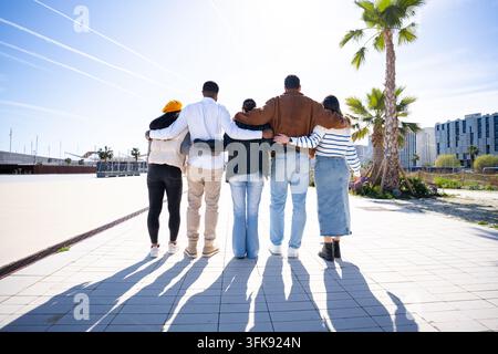 Verschiedene junge Freunde gehen zusammen und umarmen Freundschaft und Einheit Stockfoto