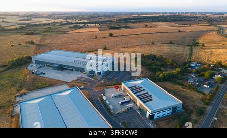 Luftbild von Industriegebäuden, umgeben von ländlichen Feldern und Straßen während des Sonnenuntergangs im goldenen Licht in Wellingborough, England, Vereinigtes Königreich. Stockfoto