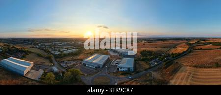 Luftaufnahme von Industriegebäuden, umgeben von ländlichen Feldern und Straßen bei Sonnenuntergang in Wellingborough, England, Vereinigtes Königreich. Stockfoto