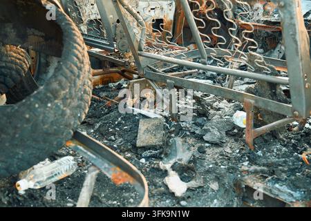 Geschmolzenes rostiges Lenkrad im zerstörten Autoinnenraum Stockfoto
