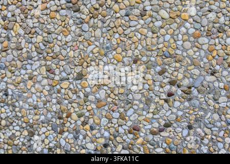 Detaillierte Nahaufnahme-Textur von gewaschenem Betonzuschlag mit kleinen bunten Kieselsteinen und Steinen Stockfoto