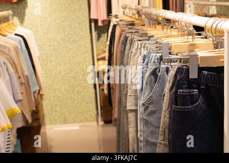 Jeans und Freizeitkleidung hängen im Kleiderladen am Regal Stockfoto