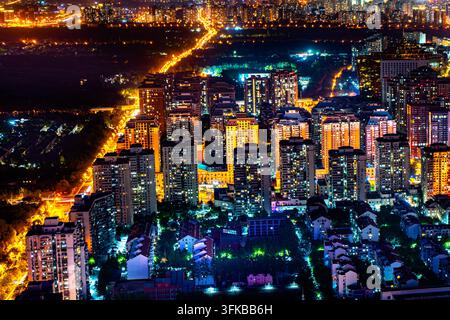 Lichtspuren vom Verkehr auf einer kurvenreichen Straße in einem Wohngebiet von Peking bei Nacht Stockfoto