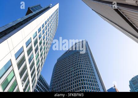 Moderne Architektur von Glas- und Stahl-Wolkenkratzern, die sich in Richtung eines hellblauen Himmels erheben Stockfoto