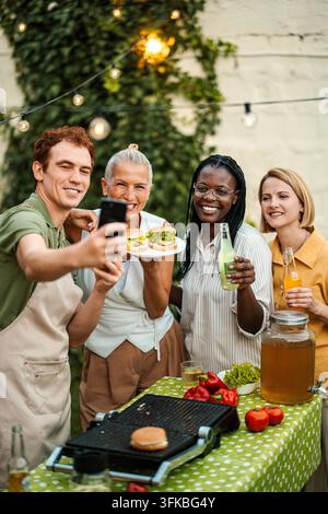 Verschiedene Freunde machen ein Selfie während einer Grillparty im Hinterhof Stockfoto