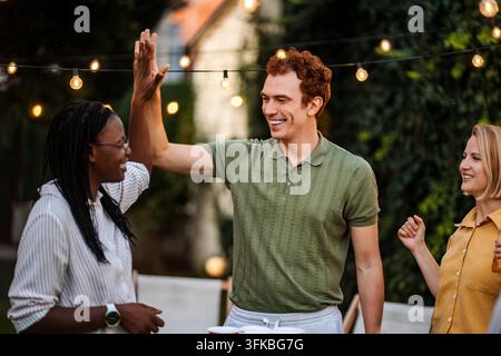 Verschiedene Freunde geben sich ein High Five auf einer Outdoor-Party Stockfoto