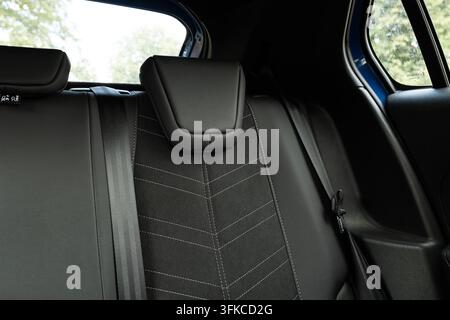 Innenfoto von modernen Auto-Rücksitzen mit dunkelgrauem Stoffbezug, geometrischer Kontrastnaht, integrierten Sicherheitsgurten und Stockfoto