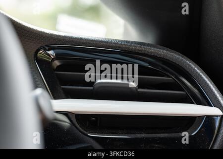 Nahaufnahme eines modernen Auto-Armaturenbrett-Luftventilationsgitters mit glänzender schwarzer Zierleiste, einem Richtungs-Lamellenclip und einem klaren weißen A Stockfoto