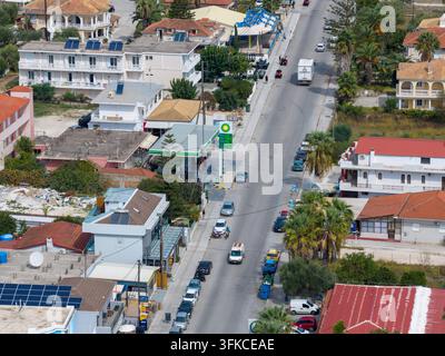 Laganas, Zakynthos Griechenland, 1. September 2026: Luftaufnahme entlang einer Hauptstraße in Laganas, die eine BP-Tankstelle, Fahrzeuge, Hotels, Wohnungen, Palmen zeigt Stockfoto