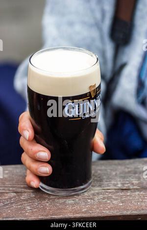 Frau hält ein Pint mit Guinness Stockfoto