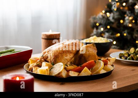 Ganzes geröstetes Huhn mit Kartoffeln und Gemüse auf festlichem Esstisch Stockfoto