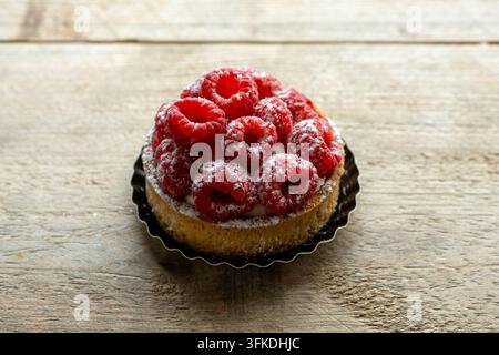 Himbeertarte mit Puderzucker auf rustikalem Tisch Stockfoto