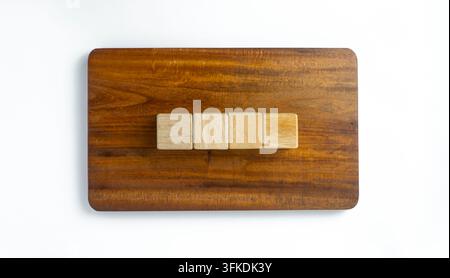 Kleine Holzblöcke, die auf einer Holzplatte gegen einen weißen Hintergrund angeordnet sind, veranschaulichen strategische Planung, Teamarbeit, Organisation Stockfoto
