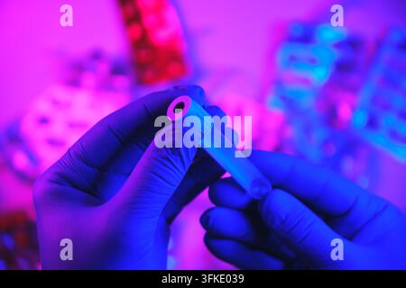 Handschuhen haltende Hände ein Reagenzglas während der wissenschaftlichen Analyse in einem lebendigen Labor Stockfoto
