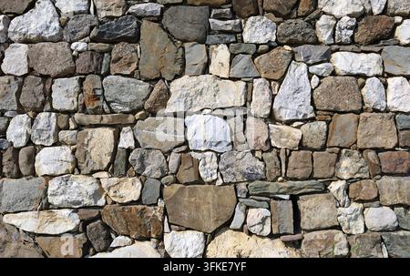 Alte rustikale Trockenmauer aus großen mehrfarbigen Steinen. Hintergrund und Textur. Stockfoto