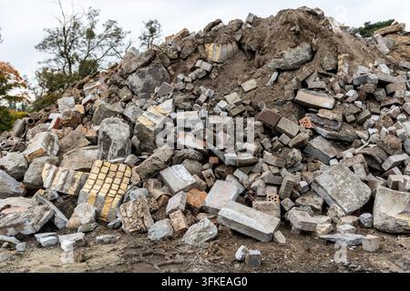 Großer Haufen von Bauschutt enthält zerbrochenen Beton, Ziegelsteine, Pflastersteine und Erde auf der Abbruchstätte. Gemischter Schutt veranschaulicht Baumüll Stockfoto