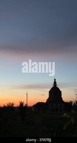Vertikale Außenlandschaft eines alten Tempelbaus, dunkle Silhouette bei wunderschönem Abenddämmerlicht. Farbiger Gradientenhimmel von dunkelblau zu orange Stockfoto