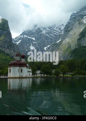 Die St. Bartholomäus-Kirche am Königssee in Berchtesgaden, Bayern, Deutschland, liegt vor dramatischen Alpenbergen. Die Kirche mit ihrem markanten roten Onio Stockfoto