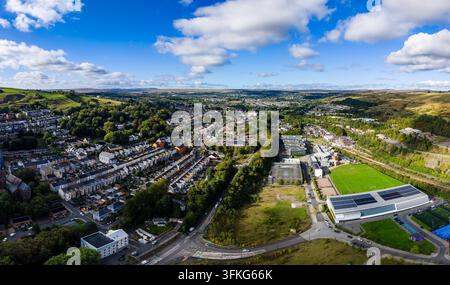 Weites Panorama über die walisische Stadt Welsh Valleys mit Reihenhäusern, Straßennetzen, Sporteinrichtungen und umgebendem Moorland, Blick aus großer Höhe Stockfoto