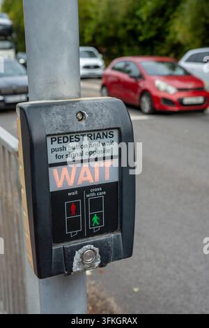 Standard-UK-Fußgängerüberweg-Druckknopfsteuerbox, die an einem Metallmast am Straßenrand montiert ist. Stockfoto