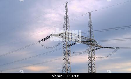 Hochspannungs-Freileitungsmasten und -leitungen vor einem bewölkten Himmel. Stockfoto