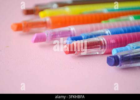 Bunte plastische mechanische Wachsstifte oder Drehstifte, die auf rosa Hintergrund angeordnet sind Stockfoto