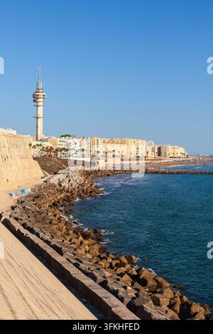 Strand Santa María del Mar und die historische Uferbefestigung entlang des Campo del Sur in Cádiz, Spanien, mit dem ikonischen Kommunikationsturm und der Atlantikküste Stockfoto
