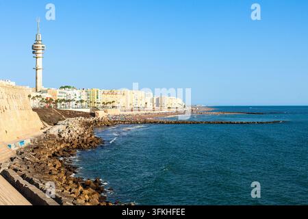 Strand Santa María del Mar und die historische Uferbefestigung entlang des Campo del Sur in Cádiz, Spanien, mit dem ikonischen Kommunikationsturm und der Atlantikküste Stockfoto
