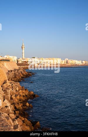 Strand Santa María del Mar und die historische Uferbefestigung entlang des Campo del Sur in Cádiz, Spanien, mit dem ikonischen Kommunikationsturm und der Atlantikküste Stockfoto