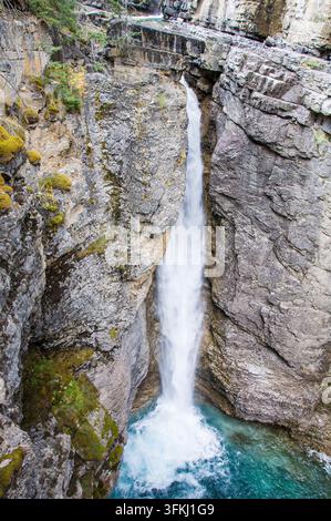 Ein spektakulärer vertikaler Hochwinkelblick auf den majestätischen Upper Falls-Wasserfall, der eine steile Kalksteinkluft im Johnston Canyon hinabstürzt. Gelegen in Stockfoto