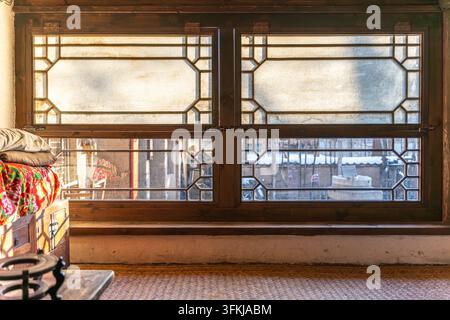 Altes ländliches Lehmhaus in China mit traditionellen chinesischen Holzgitterfenstern und Kang-Bett mit Bettwäsche Stockfoto