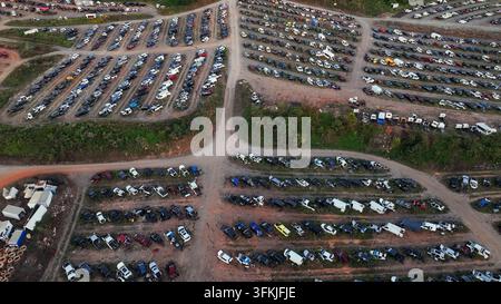 Luftaufnahme eines großen amerikanischen Schrottplatzes mit Reihen von zerstörten Autos, Lastwagen und Bussen auf einem Schotterplatz, umgeben von Bäumen. Industriegebiet einer amerikanischen Stadt a Stockfoto