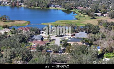 Reiche amerikanische Nachbarschaft mit Villen und Seeblick. Luftaufnahme aus der Annäherung. Sonniger Tag in der Vorstadt von Plant City, Florida. See im Hintergrund. Sonniger d Stockfoto
