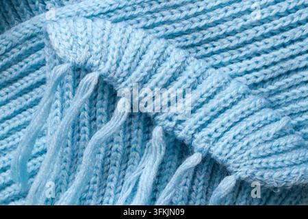 Ein blauer Wollschal mit Quasten im Nahaufnahme. Ein Element eines warmen gestrickten Schals. Stockfoto