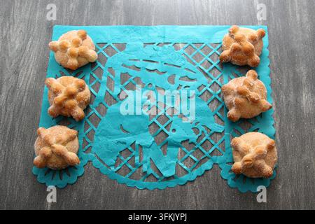 Papel-picado-Tischdecke auf Holztablett als mexikanische Tag-der-Toten-Dekoration mit köstlichem, fluffigem und zuckerhaltigem Brot der Toten Stockfoto