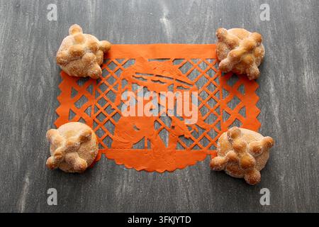 Papel-picado-Tischdecke auf Holztablett als mexikanische Tag-der-Toten-Dekoration mit köstlichem, fluffigem und zuckerhaltigem Brot der Toten Stockfoto